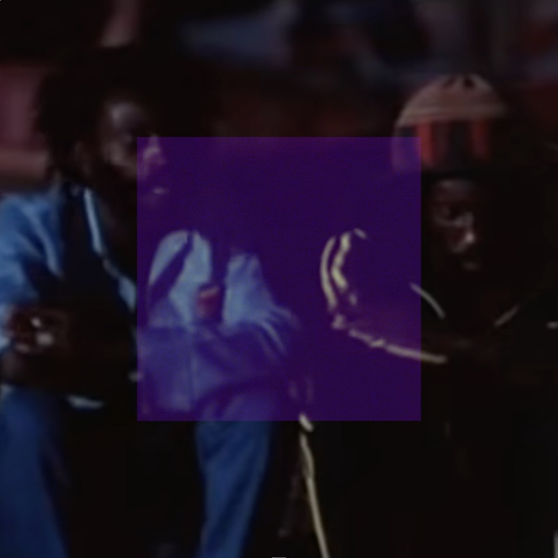 A dim, low-contrast performance photograph showing several figures in a dark indoor setting. A centered deep violet-purple square covers the middle third of the image, rendering the figures within it as blue-purple shapes with faint lime-yellow highlights. To the left, a figure in light blue clothing is visible outside the distortion. The surrounding image is dark and muted with warm reddish ambient light.